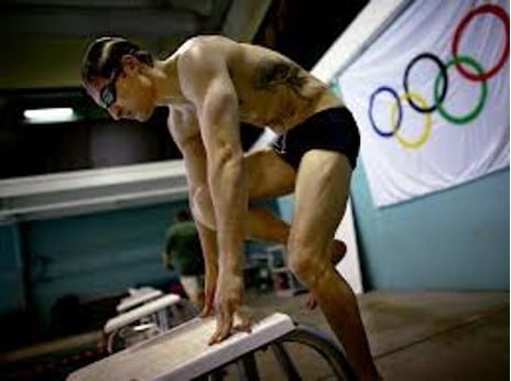 Brad S stepping onto diving platform with Olympic Rings backdrop