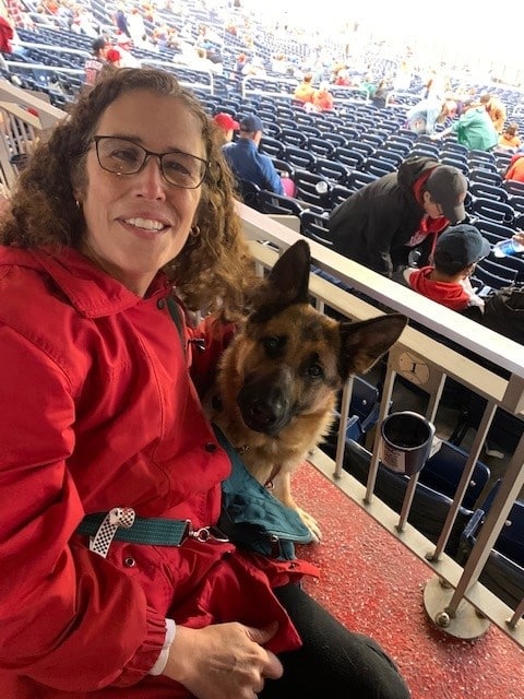 Marien smiling with Keela looking up at the camera in a baseball stadium