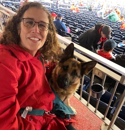 Marien and her guide dog Keela in the stands at a baseball game.