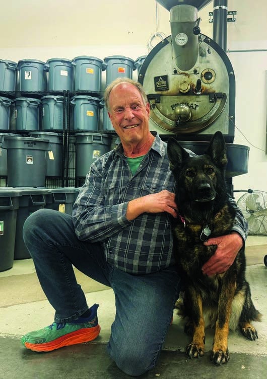 Gerry kneeling and smiling at camera while putting his left arm around Devyn, a sable GSD, who is also looking at camera.